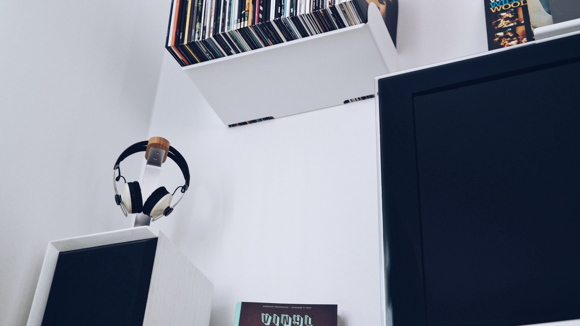 A modern entertainment area featuring headphones, vinyl records, and a television in a minimalistic room.