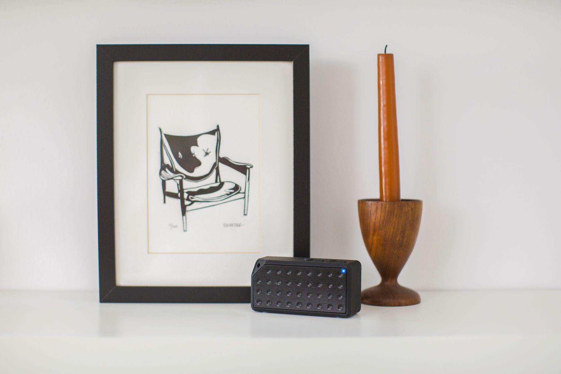 Contemporary minimalist decor with art, bluetooth speaker, and wooden candle holder.