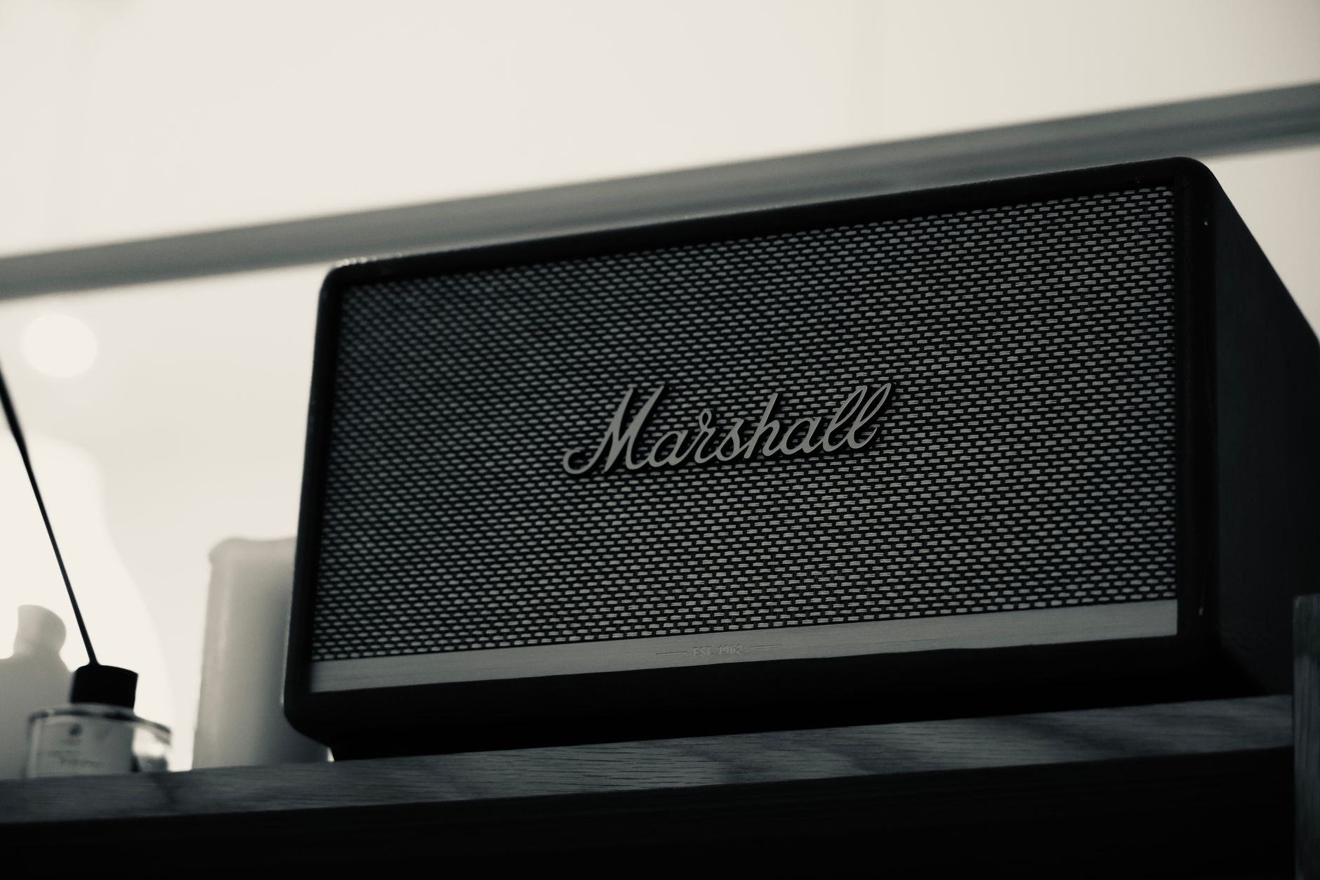 Black Marshall Bluetooth speaker on a wooden shelf, perfect for modern indoor audio systems.