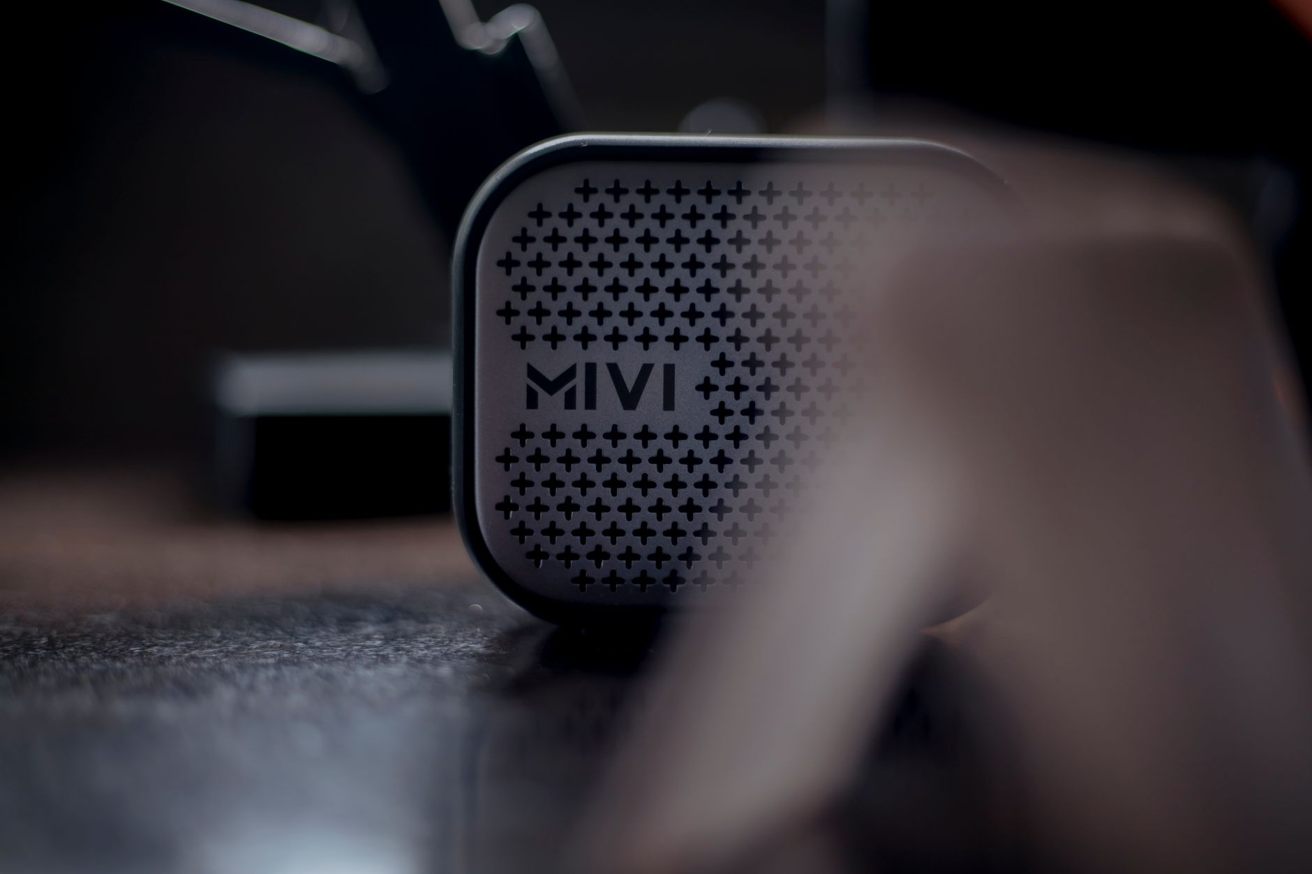 A close-up shot of a Mivi wireless speaker sitting on a wooden surface, emphasizing modern audio technology.