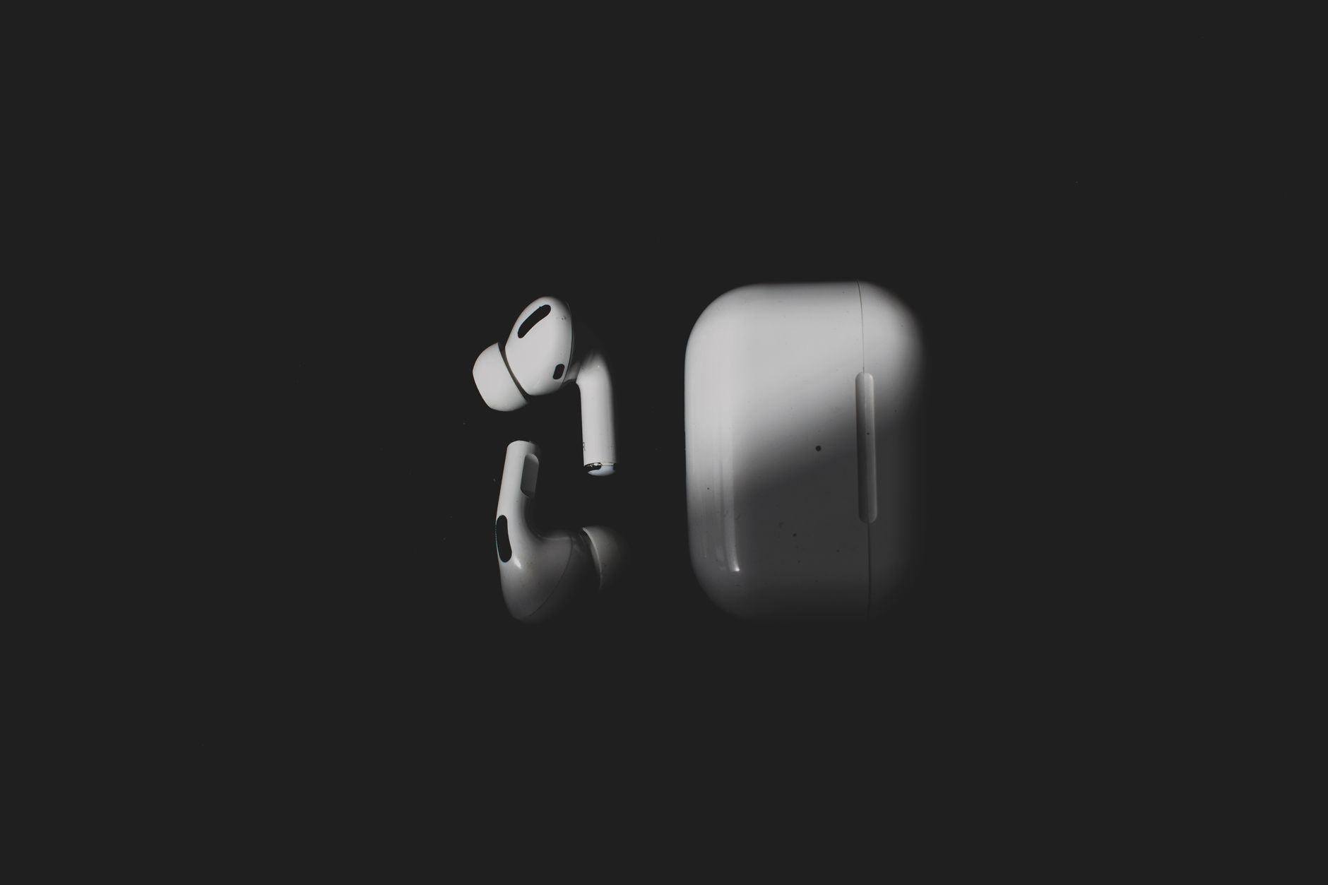 Stylish wireless earbuds and charging case on a sleek black background, featuring modern tech design.