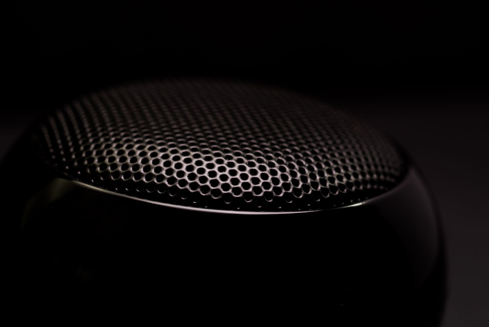 Detailed close-up of a black speaker grill, capturing its sleek and modern design