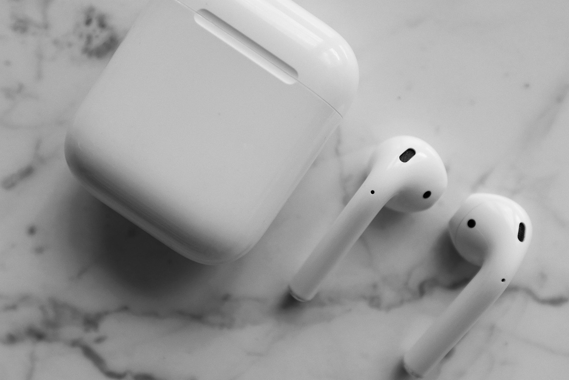 Close-up of modern wireless earphones with a case, highlighting sleek design on marble.