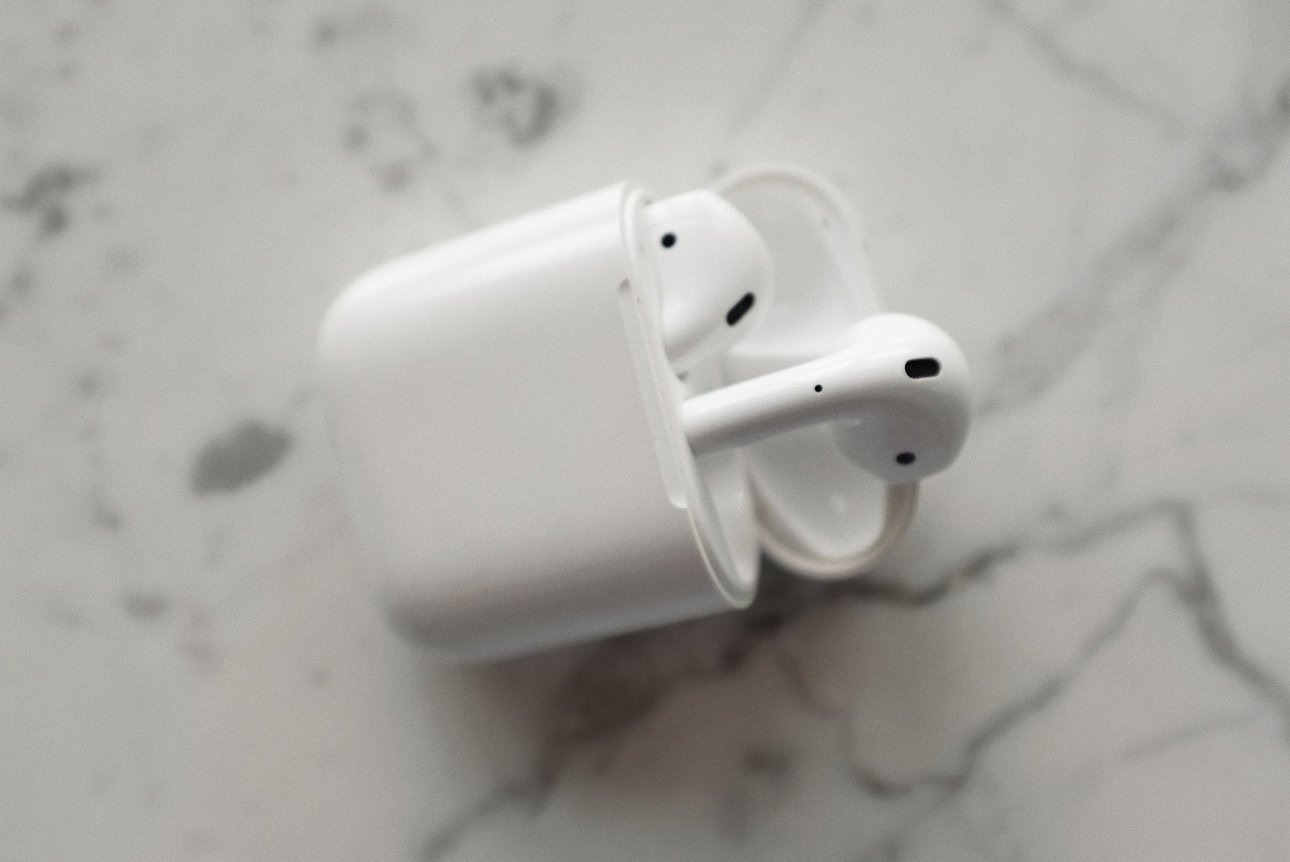 Modern wireless earphones in a sleek charging case on a marble surface.