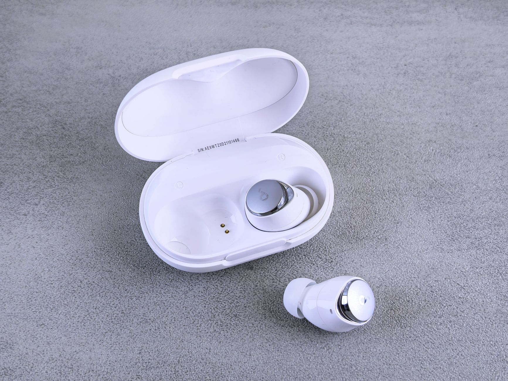 High-quality image of white wireless earbuds and charging case on a textured surface.