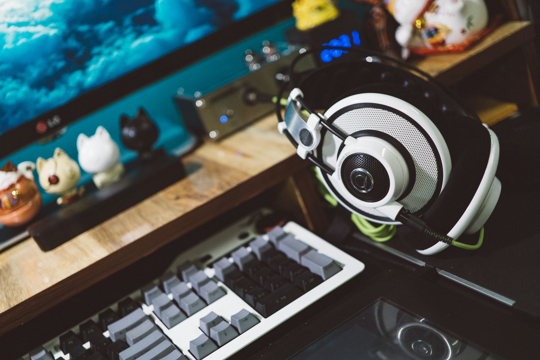 A modern desktop setup featuring stylish headphones, keyboard, and decorative figurines for a cozy tech workspace.