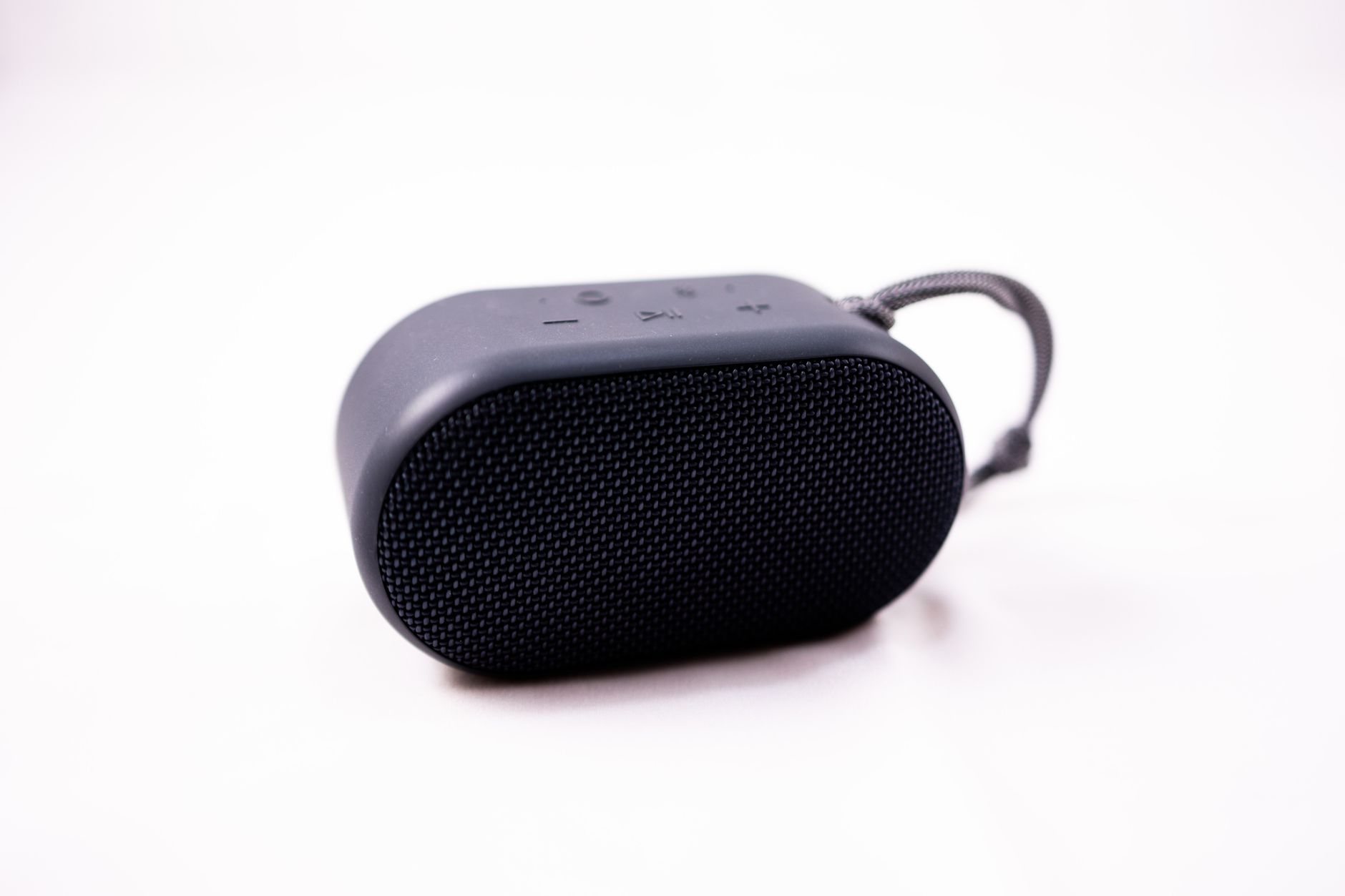 A stylish compact portable speaker with a textured exterior on a white background, showcasing modern technology.