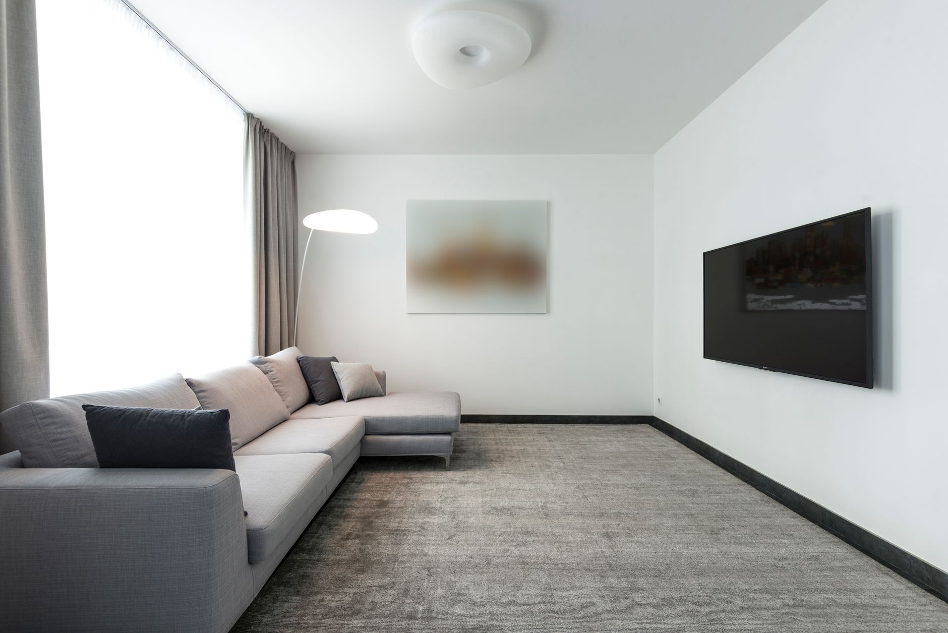 Contemporary living room with a gray sectional sofa and a wall-mounted TV.