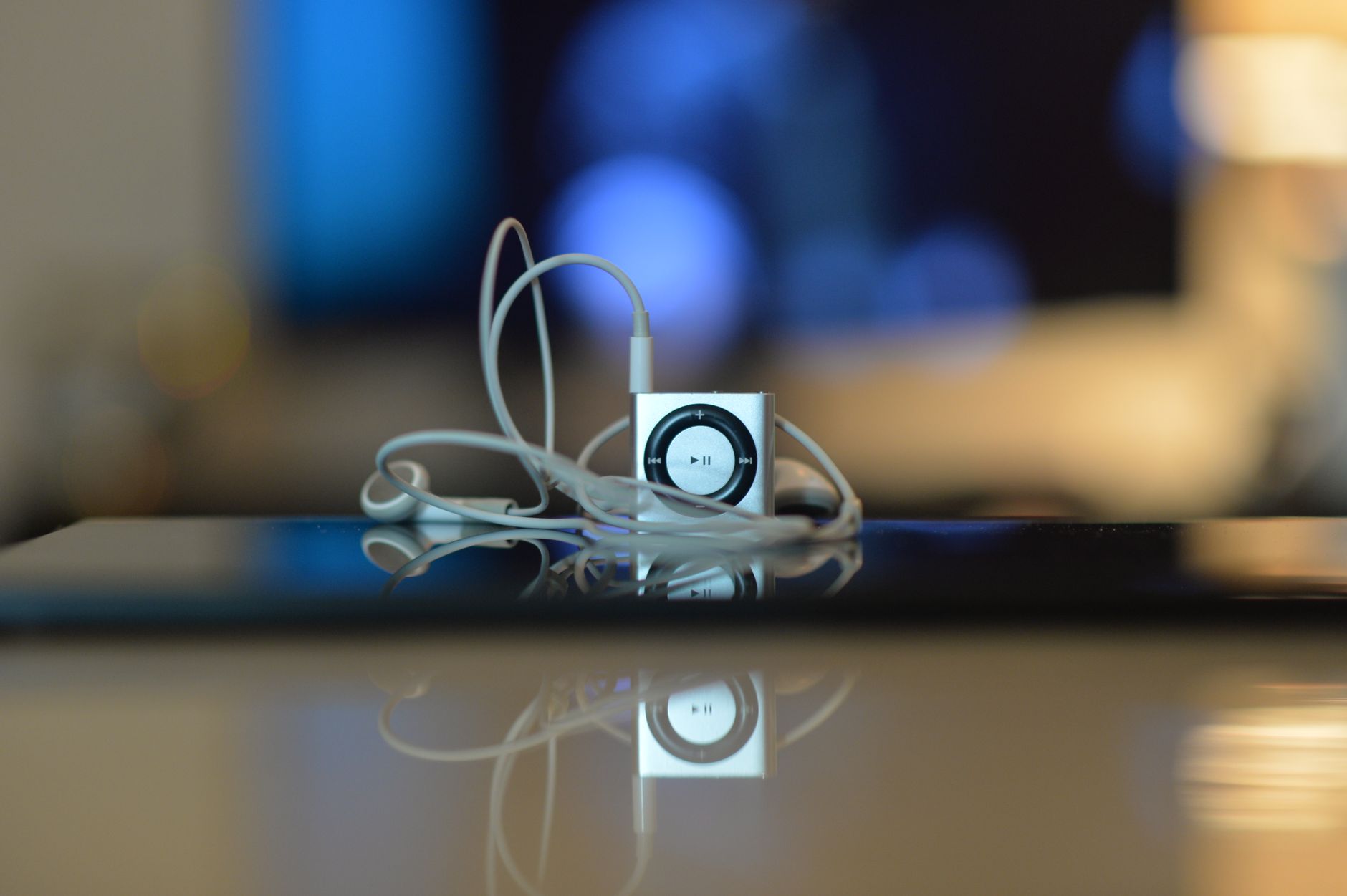 Photo of a small music player with reflective surface and earbuds, showcasing minimalist design.