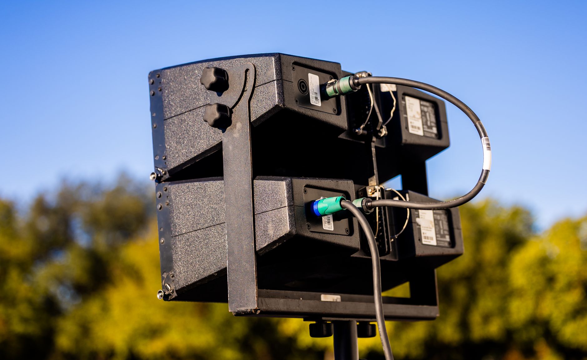 High-quality outdoor speaker setup ready for a live event against a vibrant blue sky.