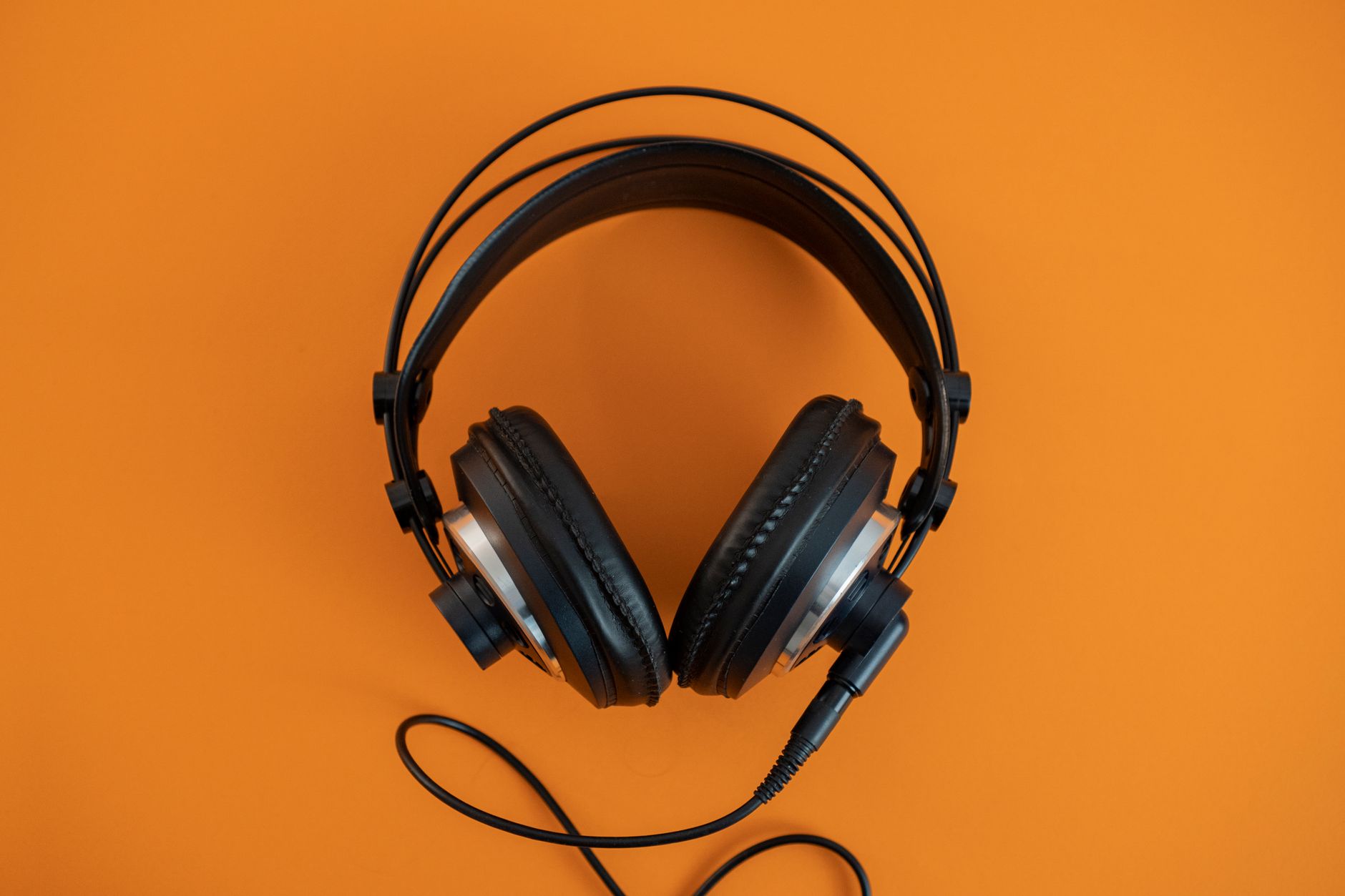 Top view of modern black headphones elegantly posed on a vibrant orange surface.