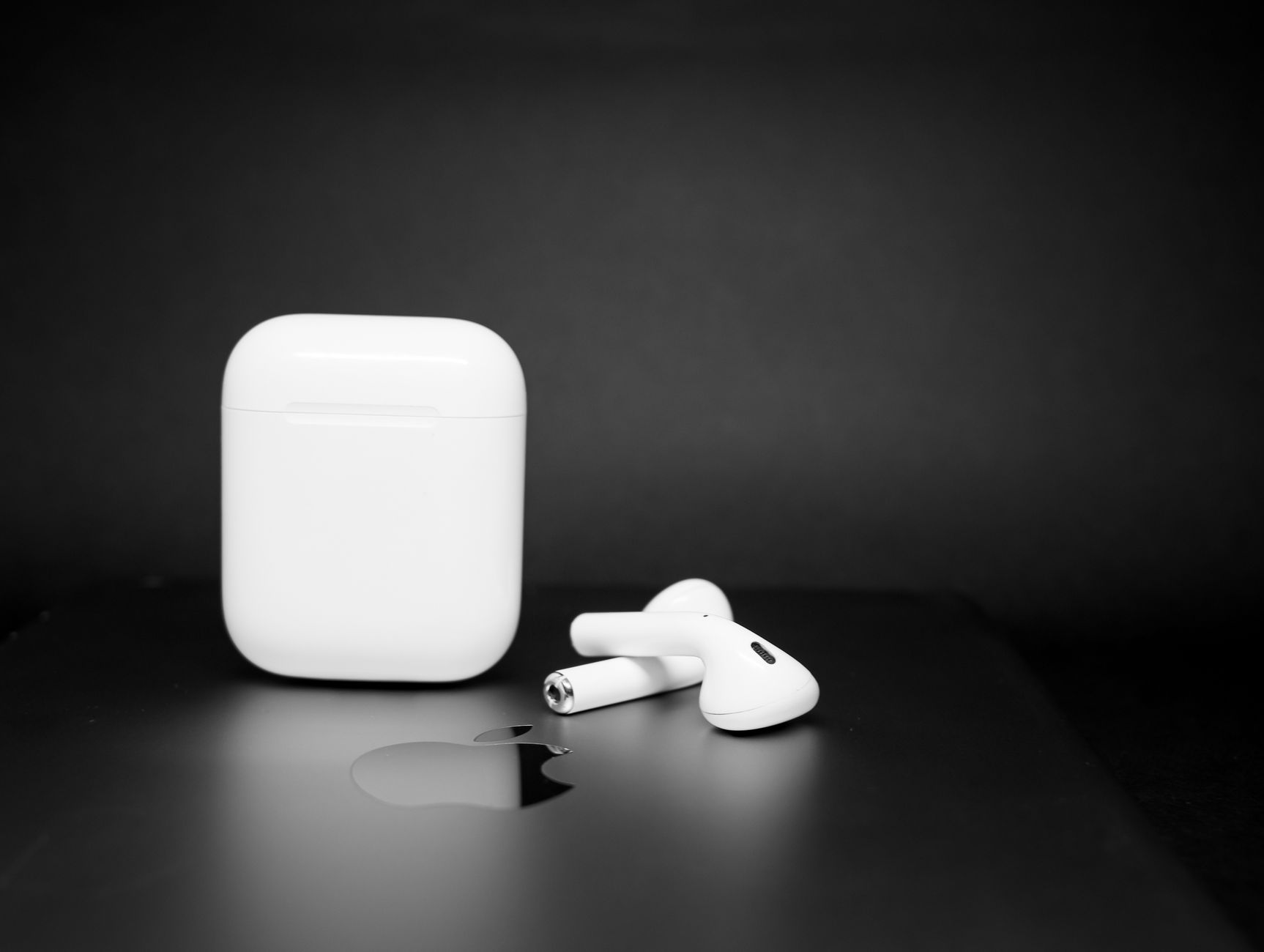 Close-up of wireless earbuds and charging case on a sleek dark background, showcasing modern design.