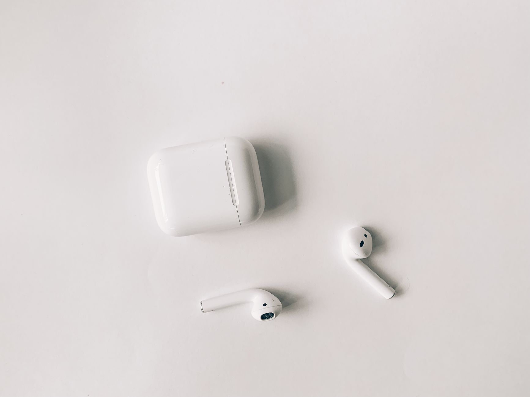Clean minimalist flat lay featuring wireless earbuds and case on a white background.
