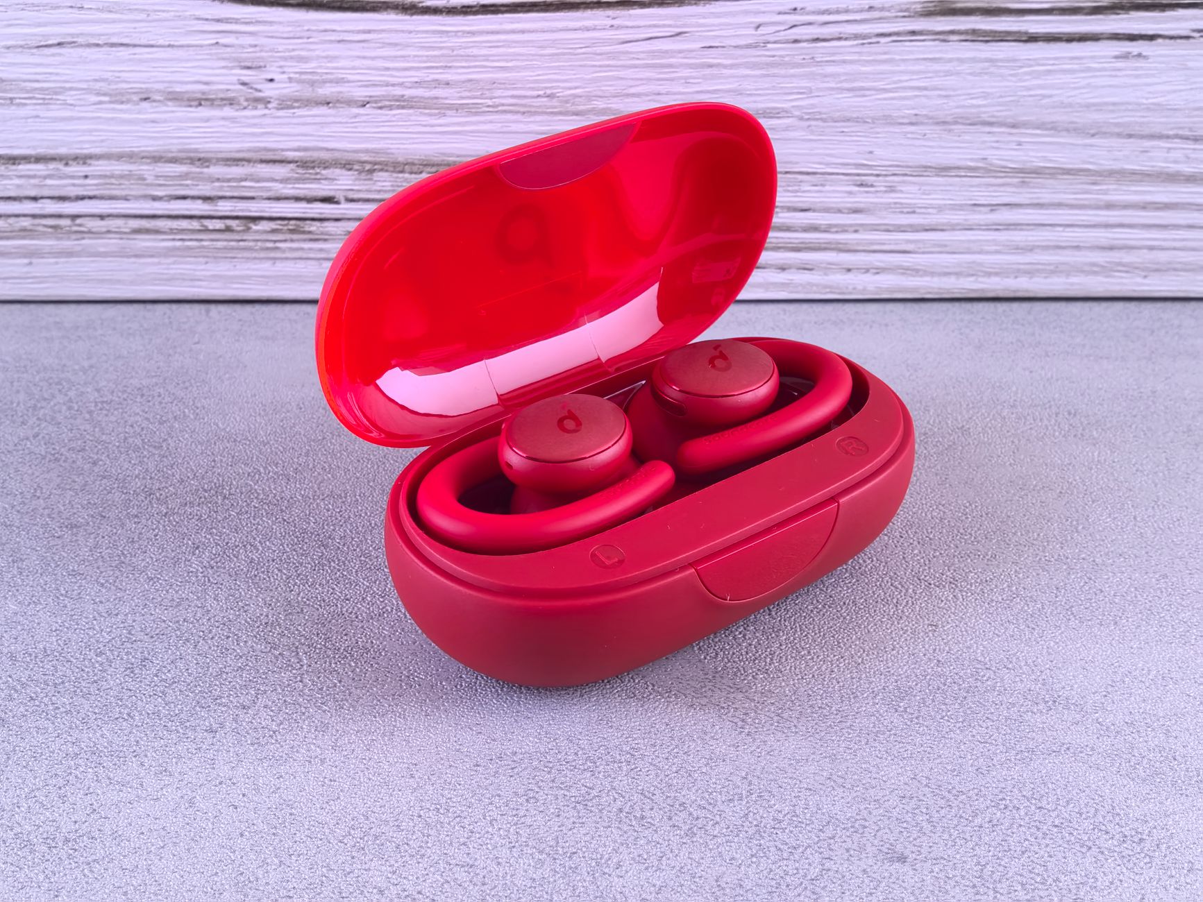 Vibrant red wireless earbuds in a sleek charging case on a modern background.