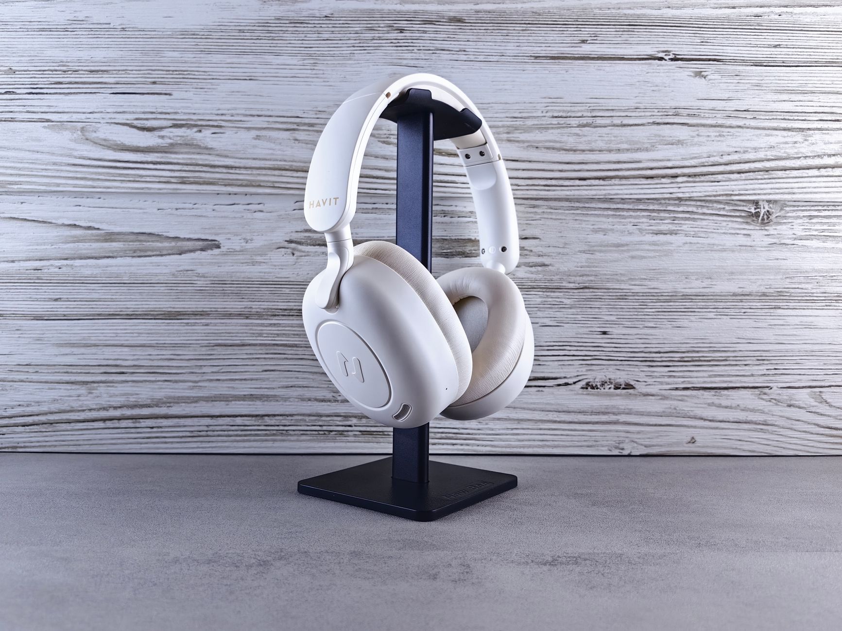 Minimalist photo of white wireless headphones on a stand against wood background.