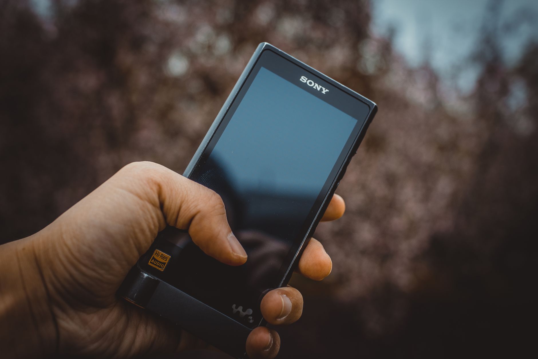 Close-up of a hand holding a portable audio device with high-res audio support.