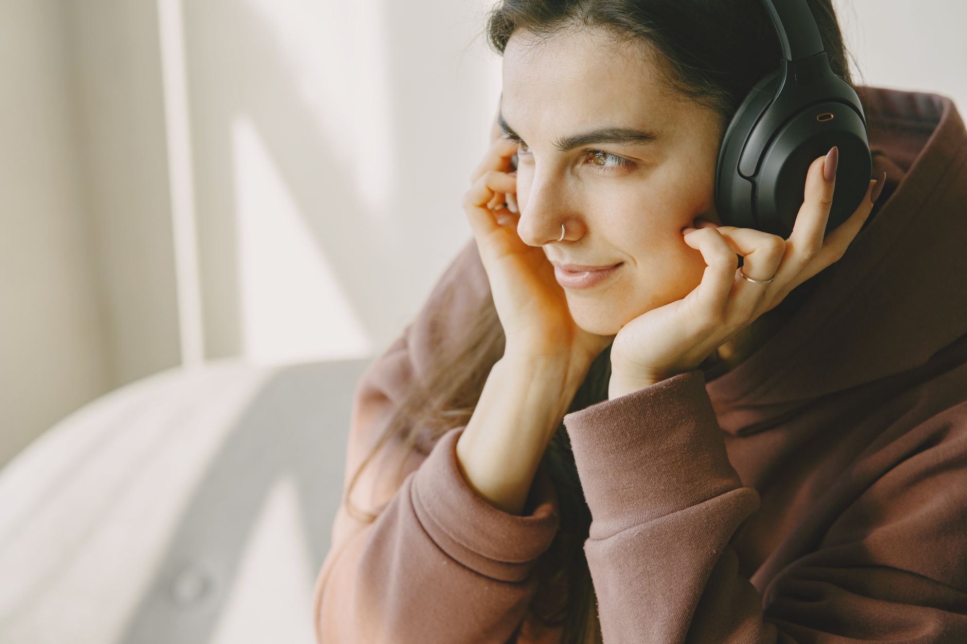 Portrait of a woman relaxing and enjoying music with wireless headphones indoors.
