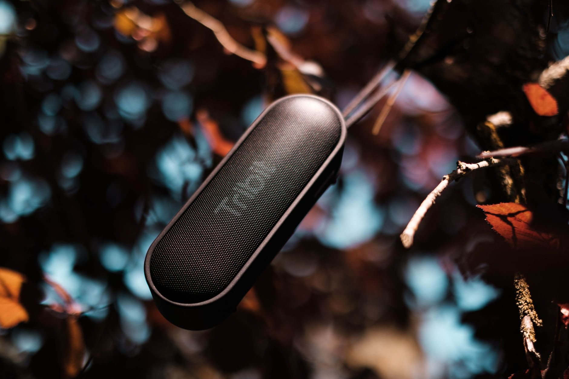 From above of contemporary design wireless speaker with shiny black surface on glass in evening