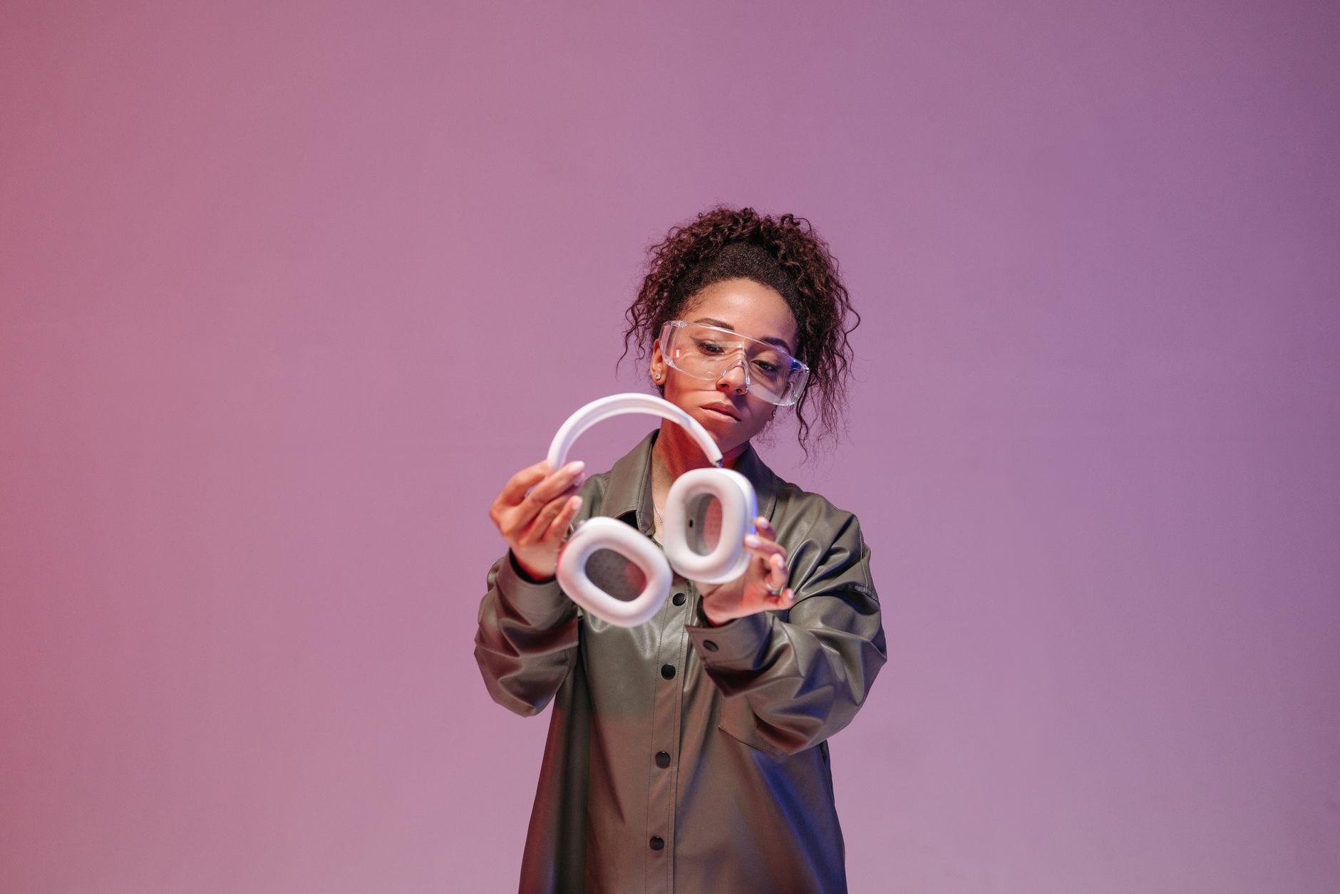 A stylish woman in a leather jacket holding modern wireless headphones, showcasing technology.