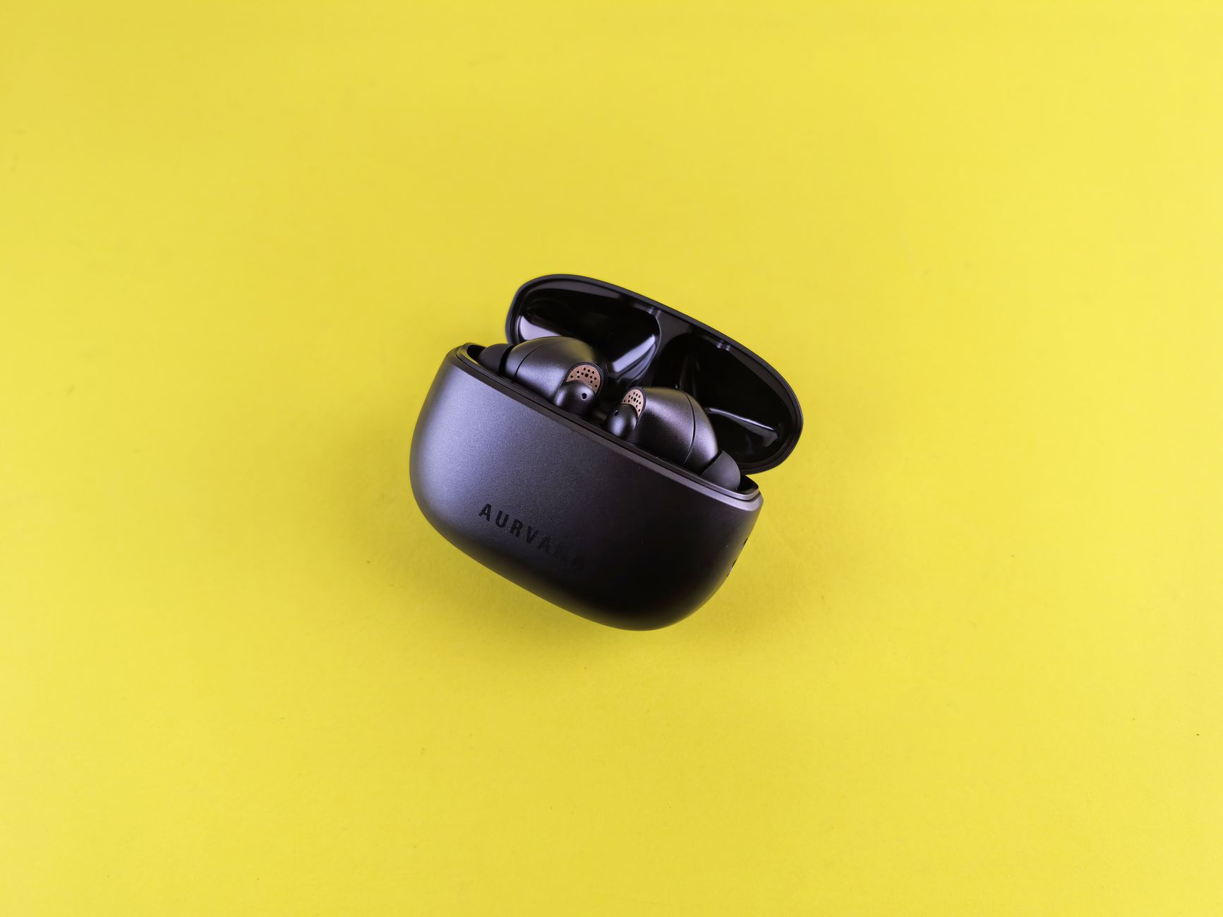 Close-up of modern black wireless earbuds in charging case on a vibrant yellow background.