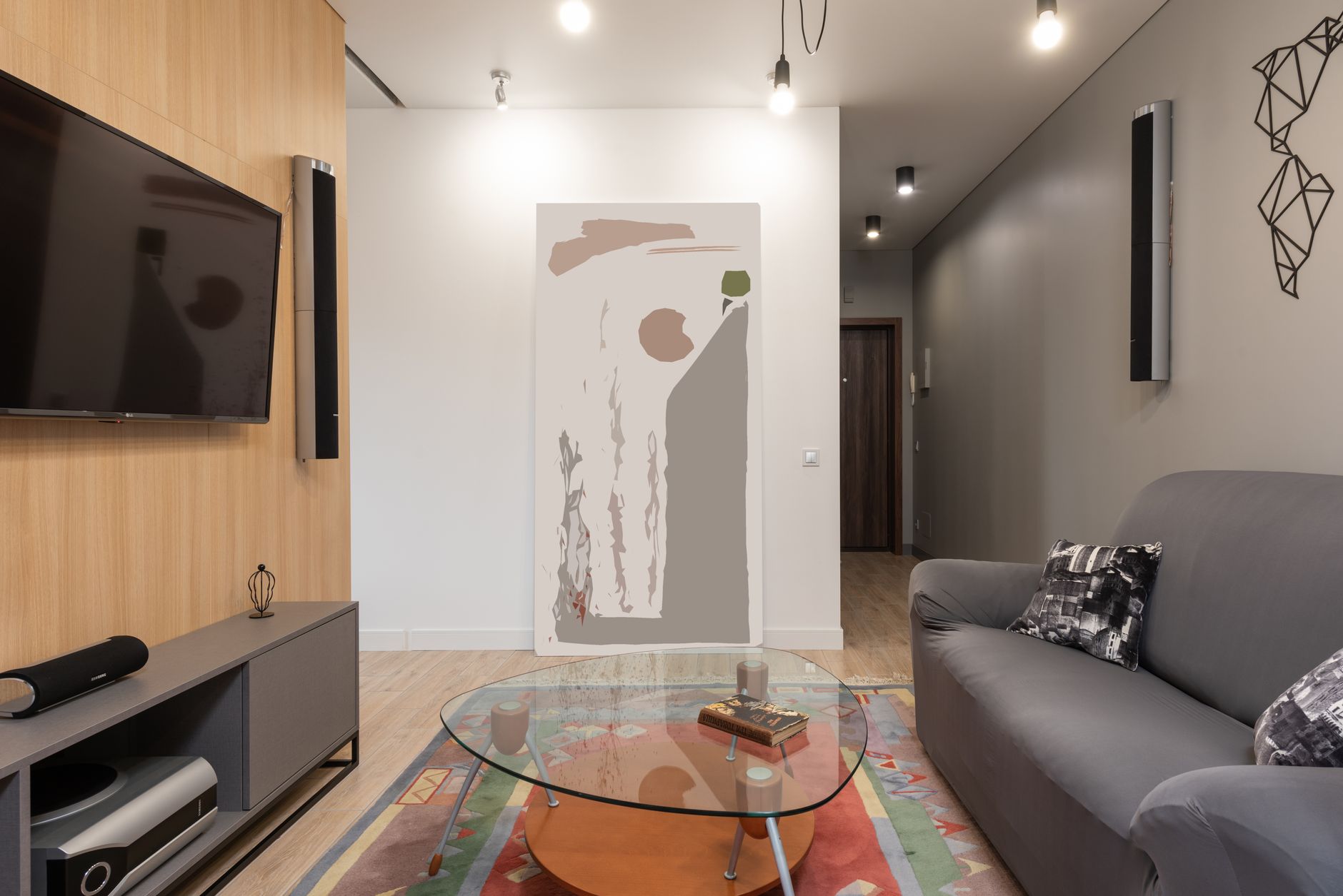 Modern apartment interior with sofa with pillows near glass table on carpet near cabinet and TV with speakers on wall near lamp on ceiling a