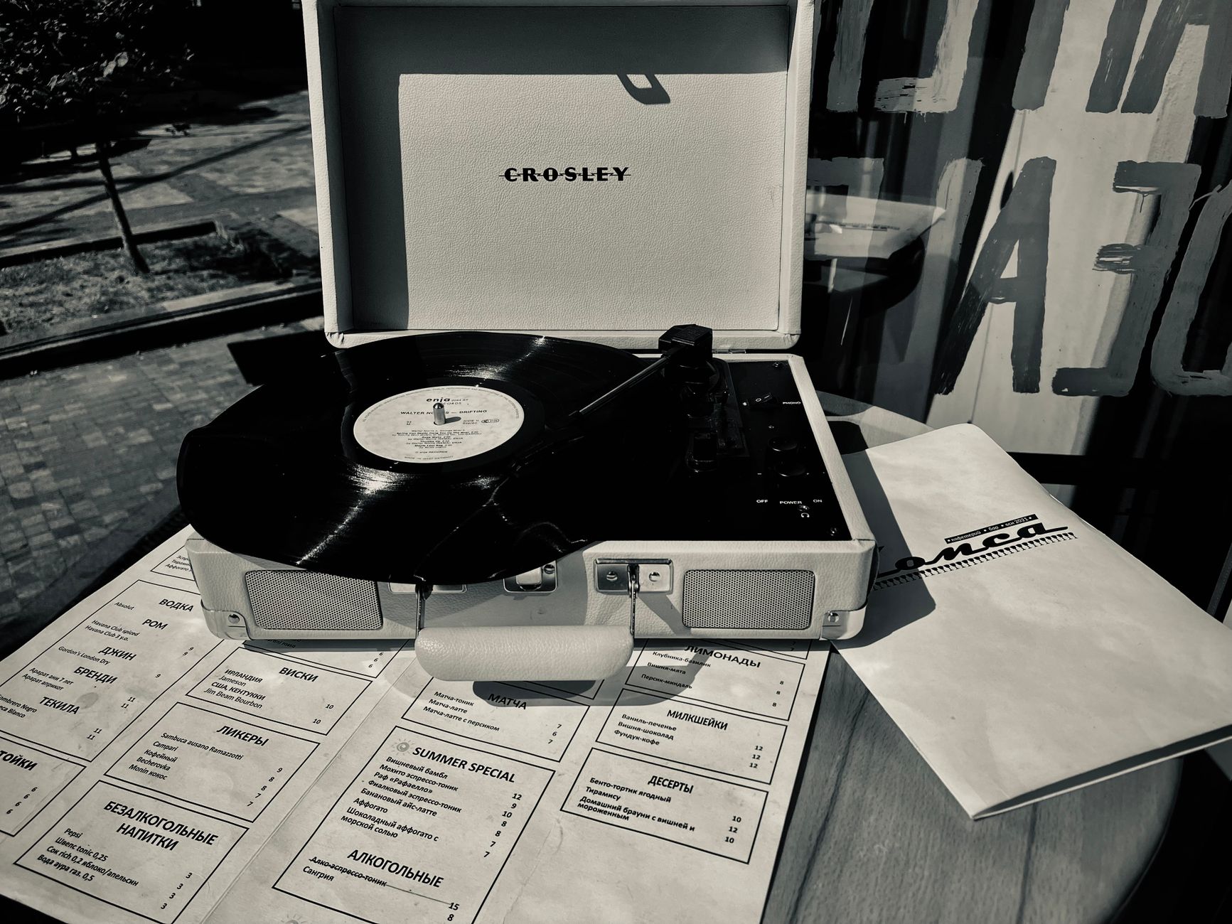 A retro Crosley turntable playing a vinyl record on a summer day outdoors.