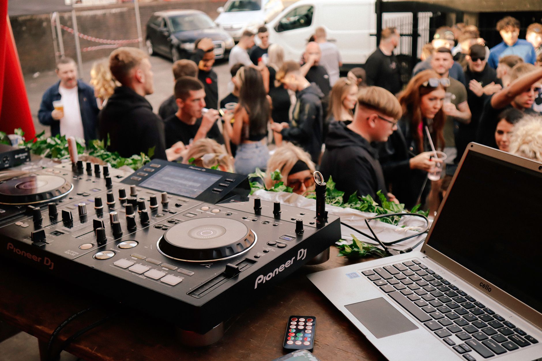 Lively outdoor music festival featuring a DJ setup with a crowd enjoying electronic tunes.