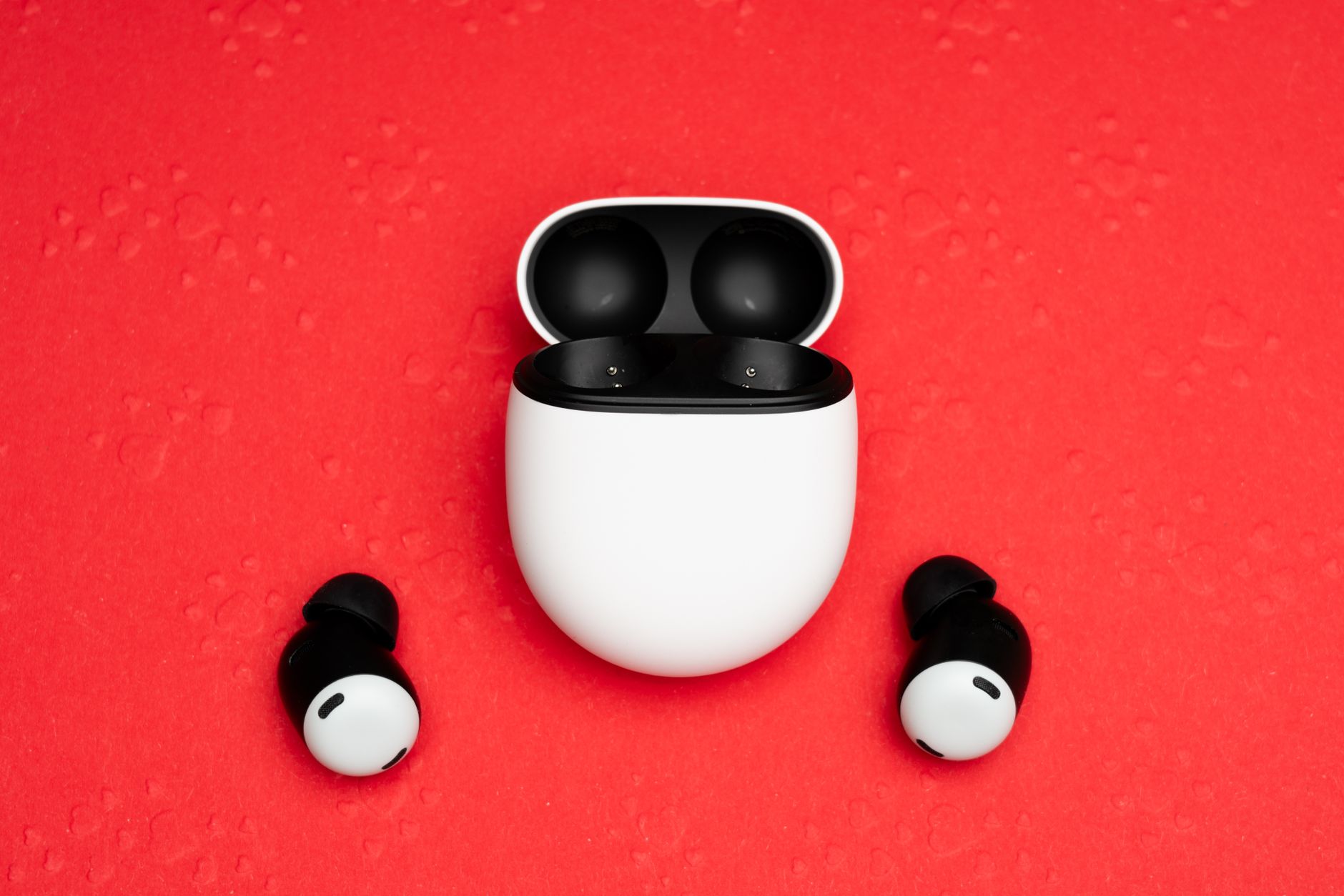 Close-up of wireless earbuds with charging case on a vivid red background, emphasizing modern technology.