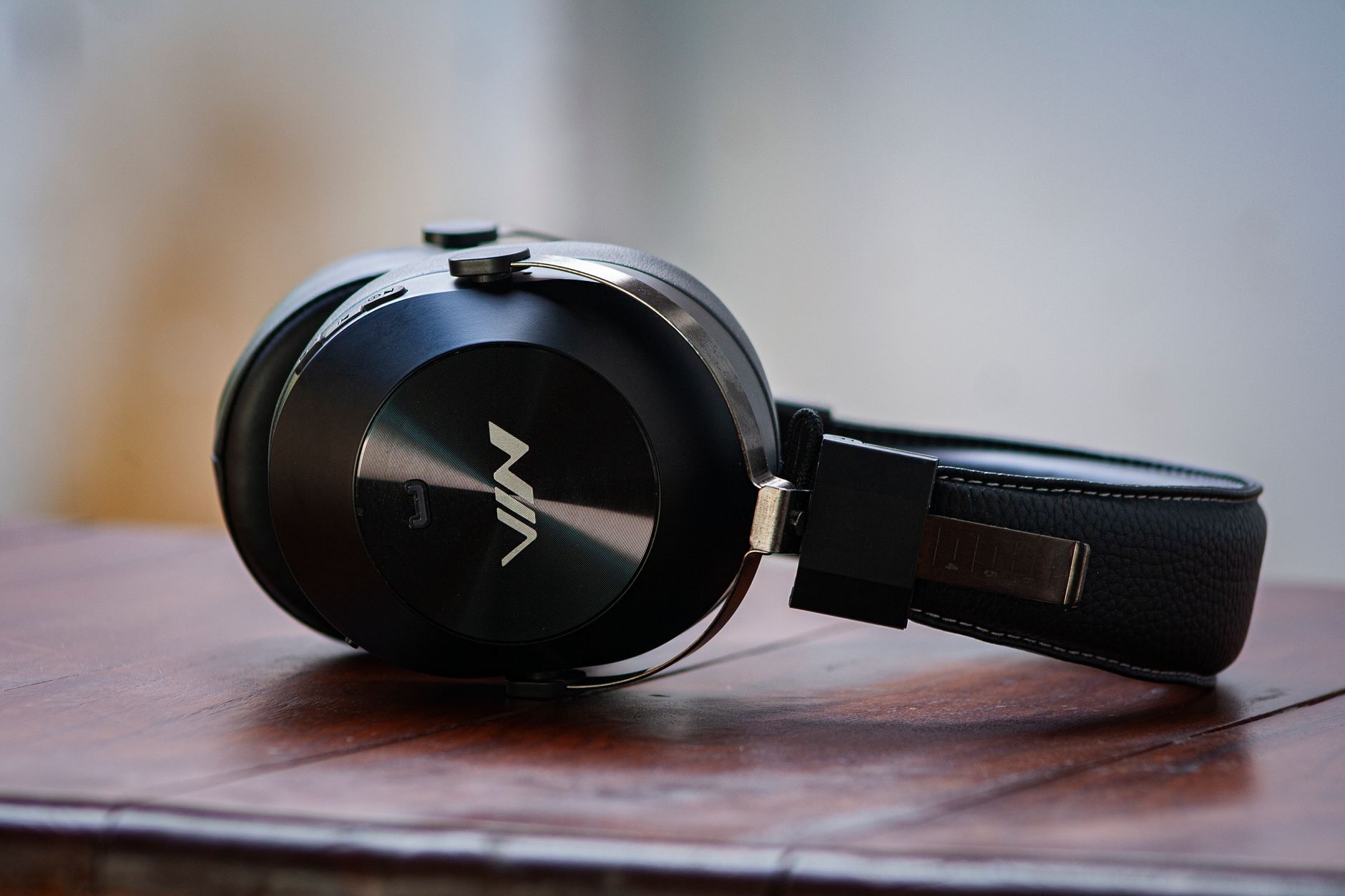 Close-up of modern black wireless headphones placed on a wooden table, showcasing style.