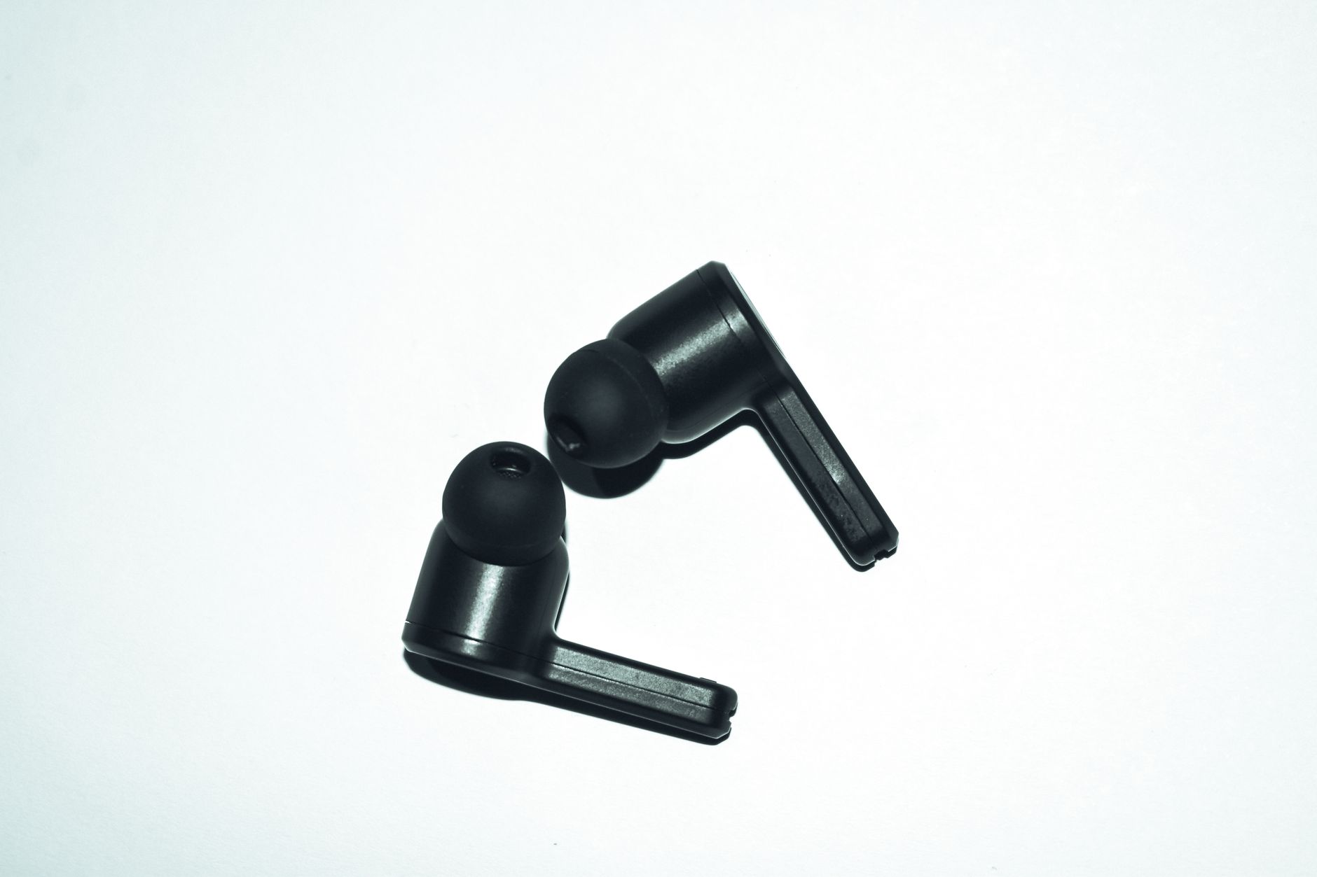 Close-up of stylish black earphones isolated on a white background, perfect for audio enthusiasts.