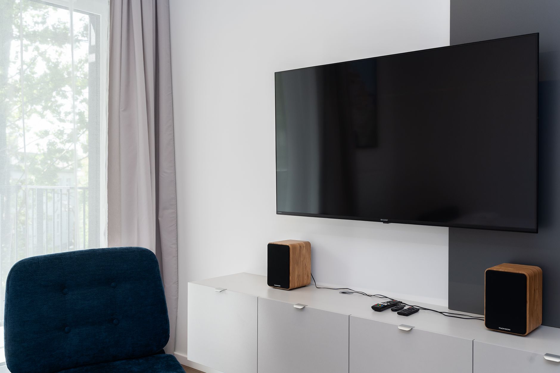 Stylish living room featuring a wall-mounted flat screen TV and sleek wooden speakers.
