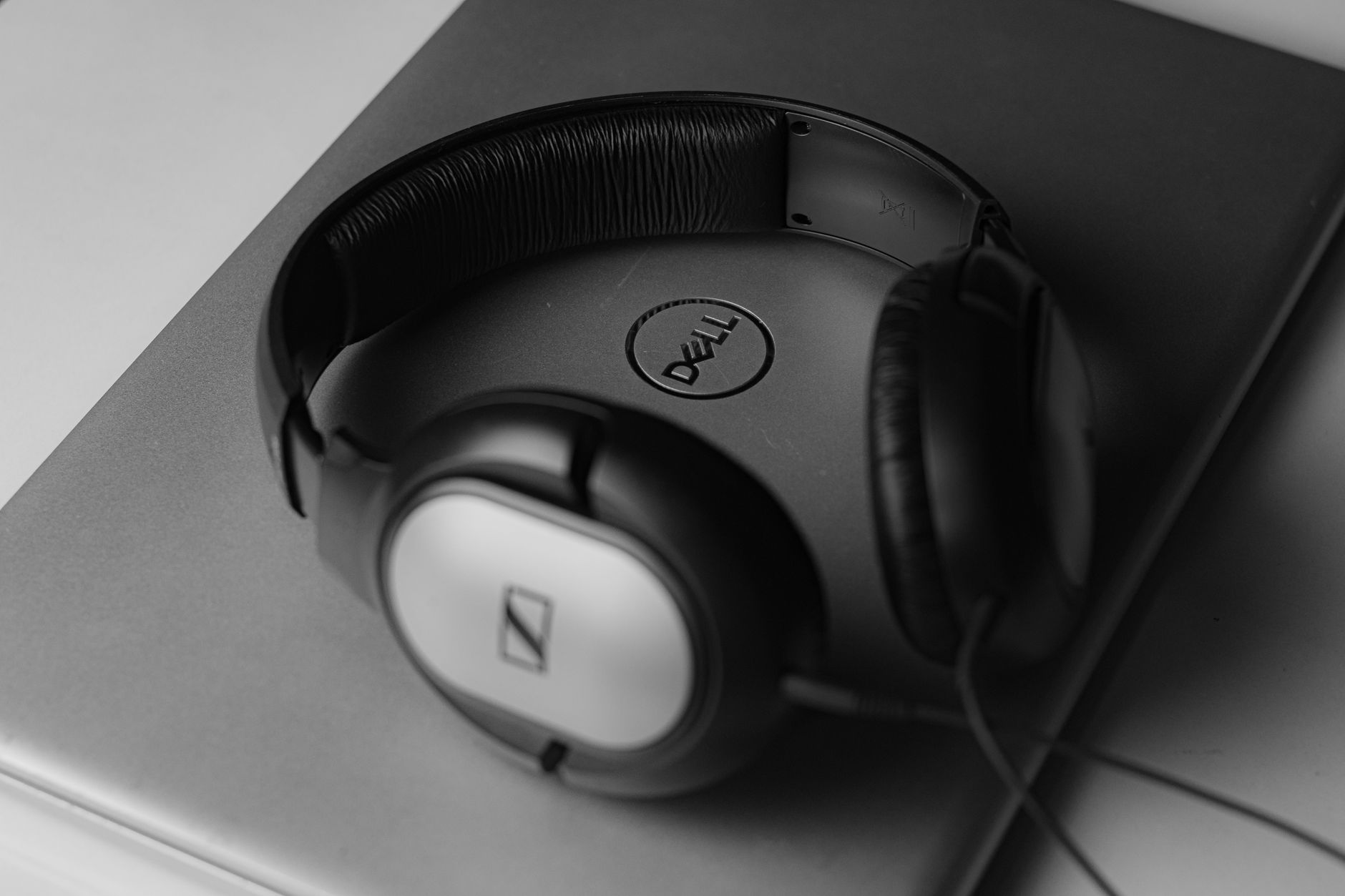 Black Sennheiser headphones placed on a Dell laptop, showcasing modern technology and minimalist design.