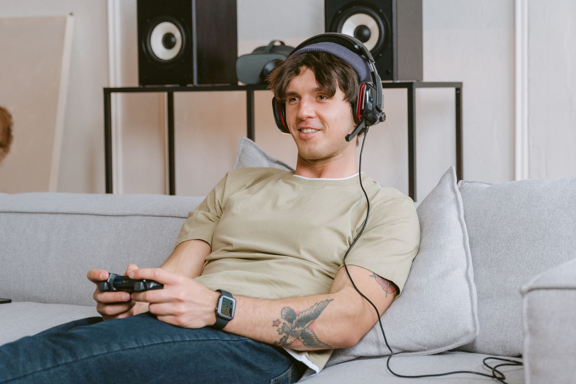 Young man enjoying video gaming session at home with a headset and controller.