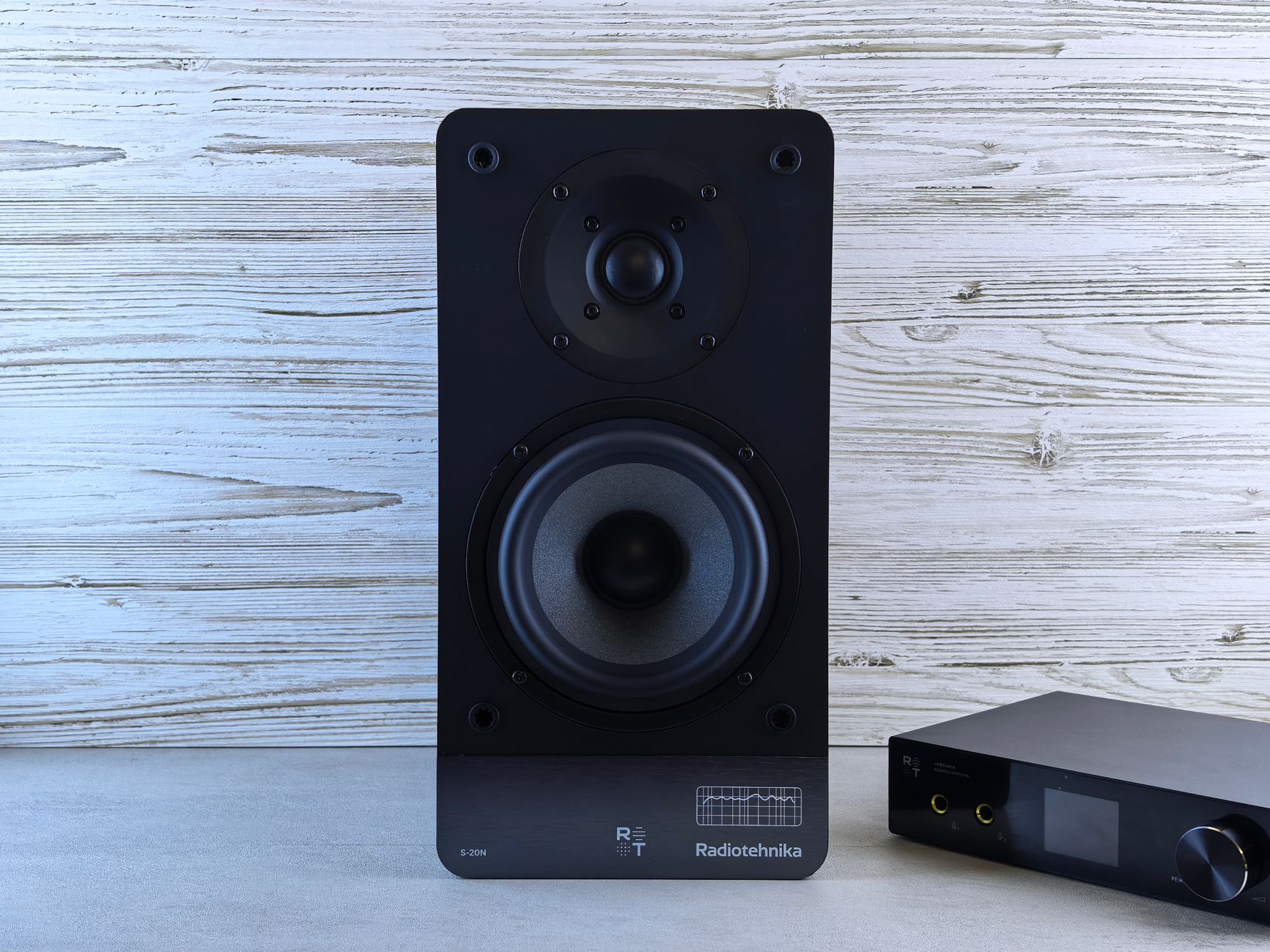 High-quality black loudspeaker and amplifier on a wood background, perfect for audio setups.