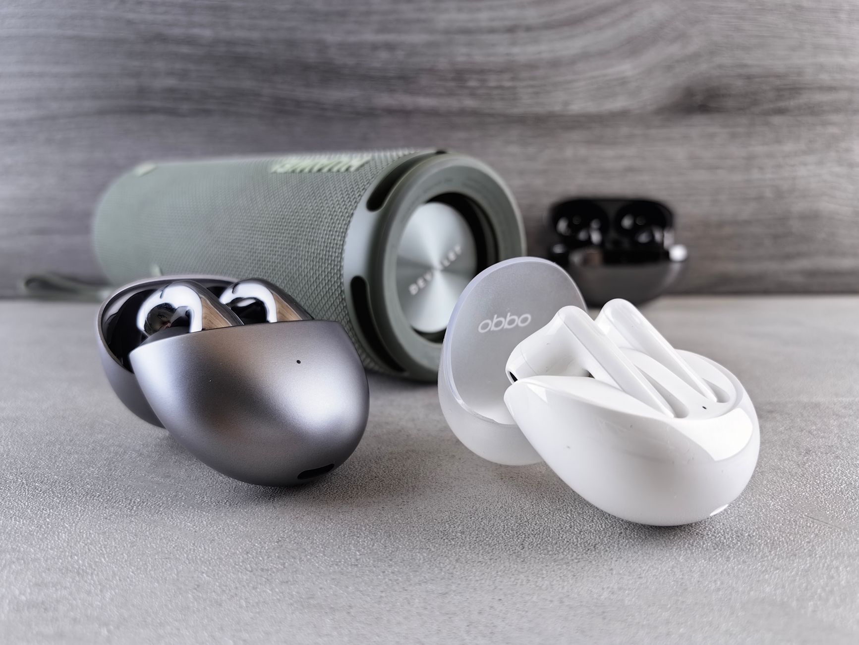 Wireless earphones and portable speaker displayed on a modern surface, showcasing sleek design and technology.