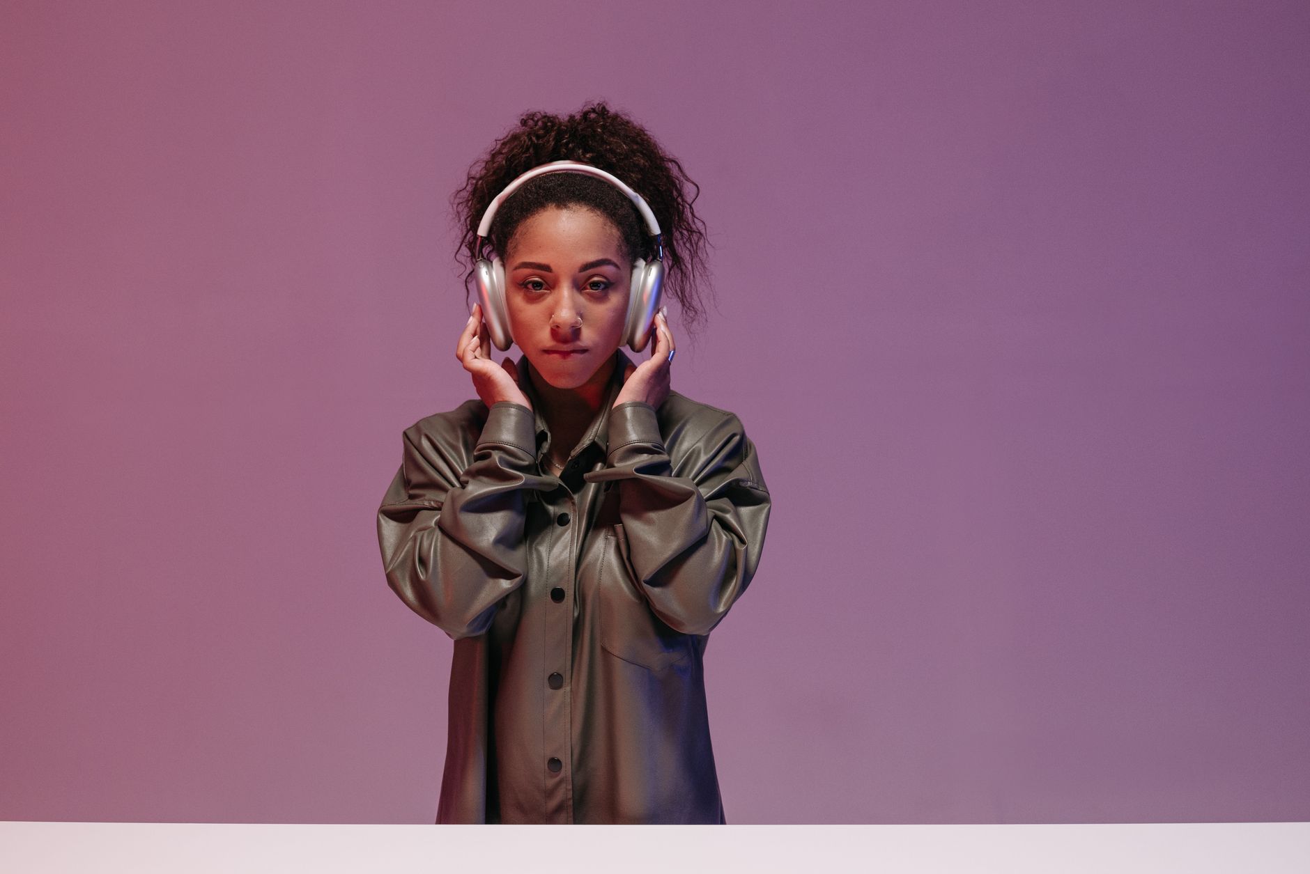 Portrait of a stylish woman in a leather jacket, enjoying music with wireless headphones.