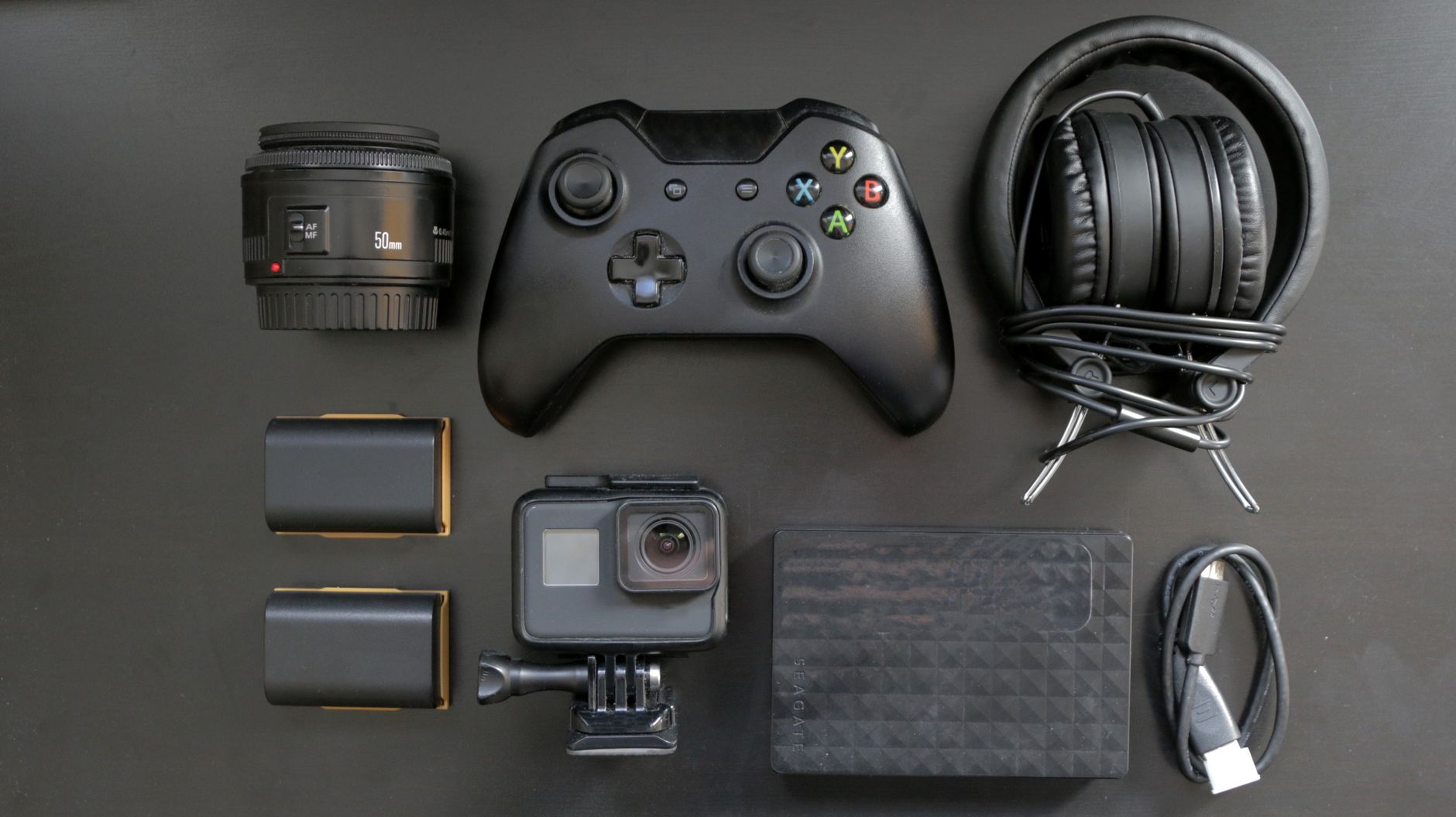 Top view of various gaming and tech gadgets, including a controller and headphones.