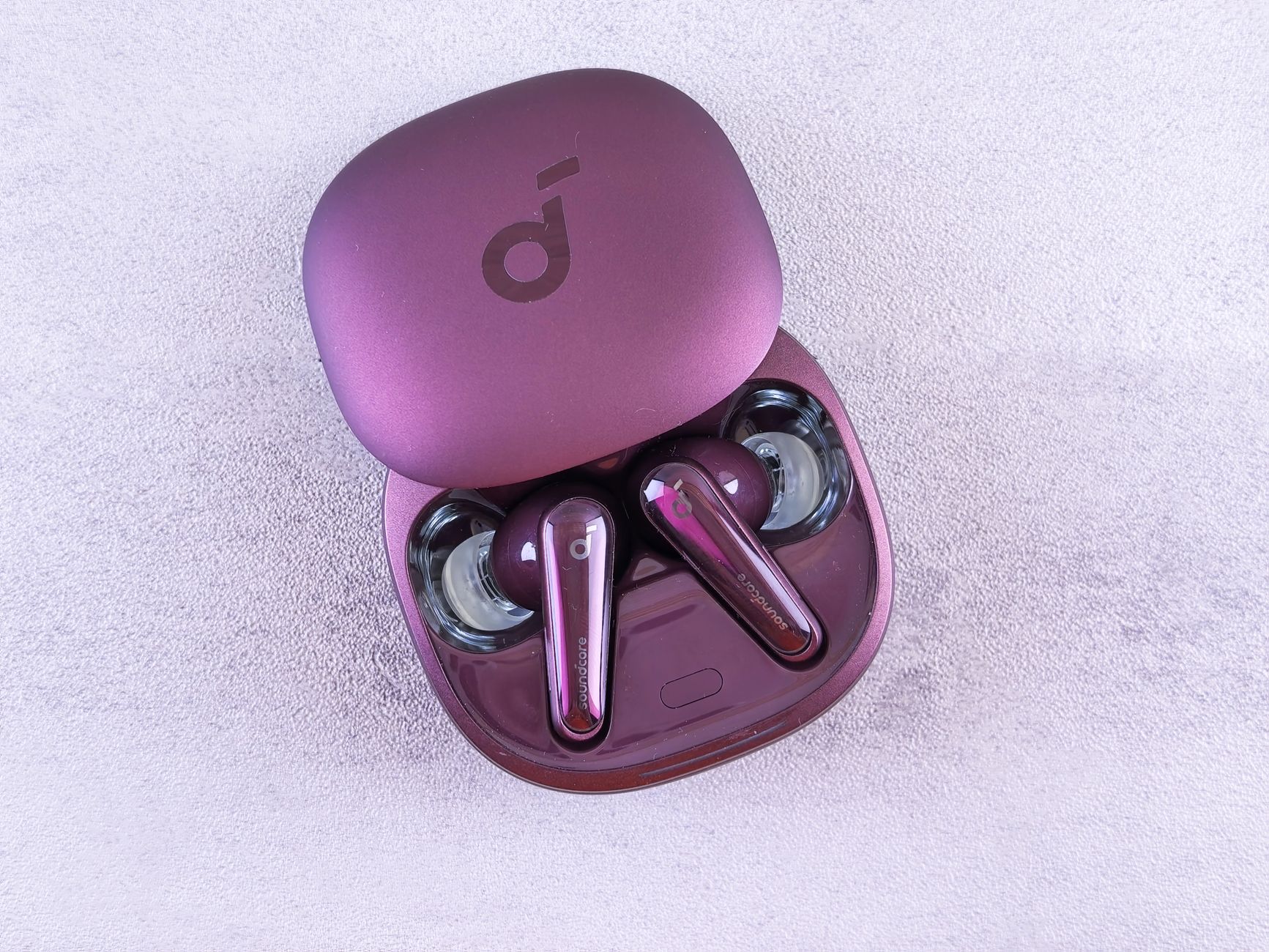 High-quality purple earbuds in an open charging case on a soft, light background.