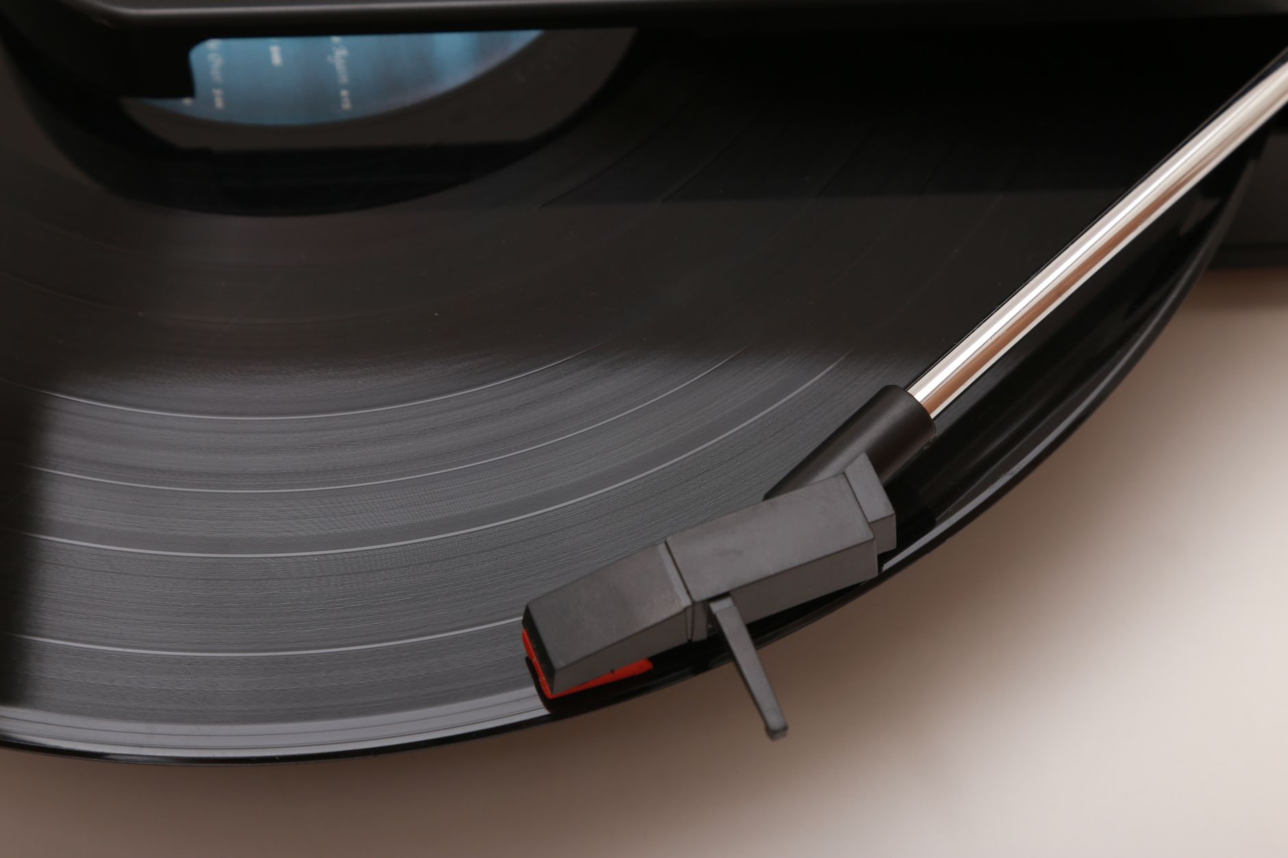 Detailed view of a vinyl record playing on a modern turntable, highlighted tonearm.