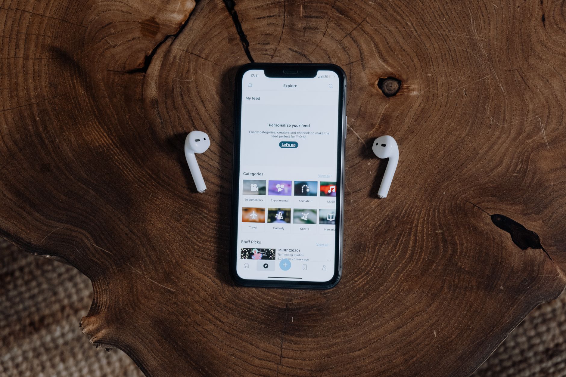 A smartphone with wireless earbuds on a rustic wooden surface, showcasing modern technology and lifestyle.