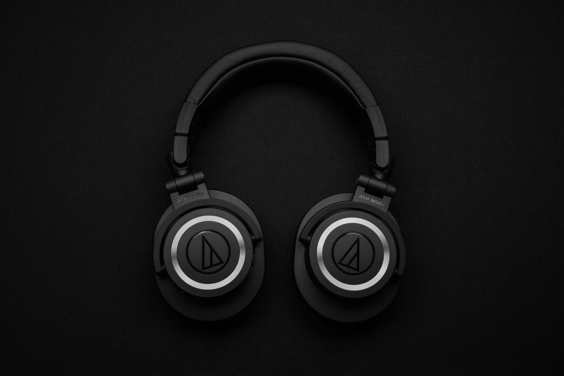 Close-up of black over-ear headphones on a black background, showcasing modern design.