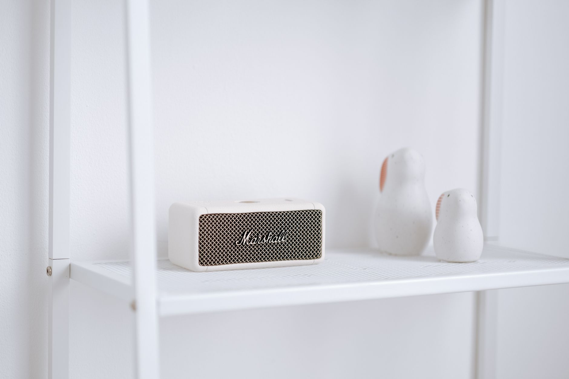 A stylish setup featuring a Marshall wireless speaker and minimalist decor on a white shelf.